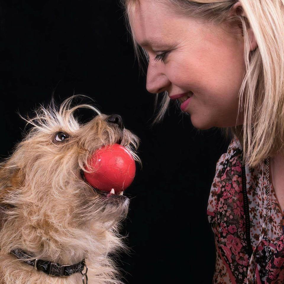 picture of caroling and her terrier dog wilma. Wilma is holding a red ball in her mouth